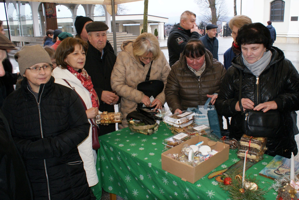 Ludzie przy stoisku podczas kiermaszu świątecznego przy sanktuarium