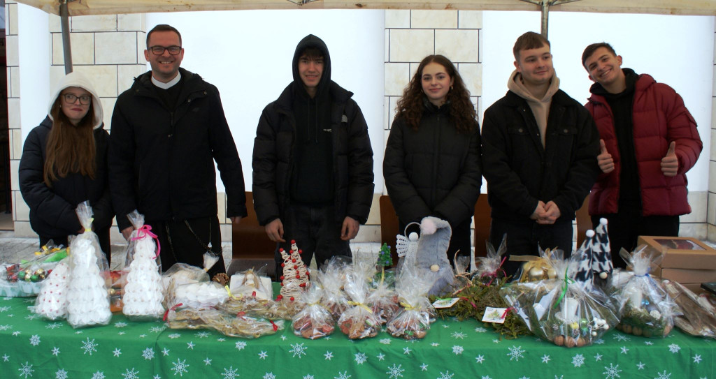 Wolontariusze oraz redemptorysta pozują do zdjęcia podczas kiermaszu świątecznego