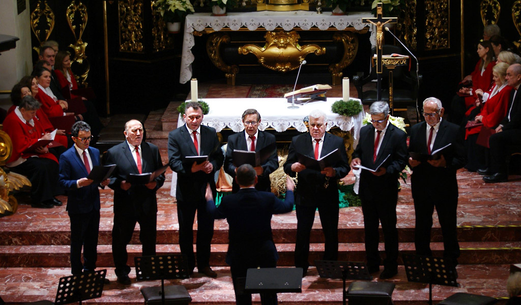 Chórzyści śpiewają na schodach prezbiterium Bazyliki Mniejszej w Tuchowie podczas koncertu kolęd