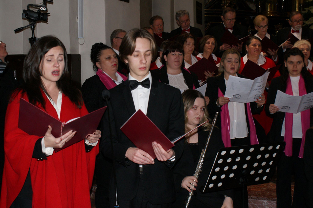 Chórzyści śpiewają na schodach prezbiterium Bazyliki Mniejszej w Tuchowie podczas koncertu kolęd