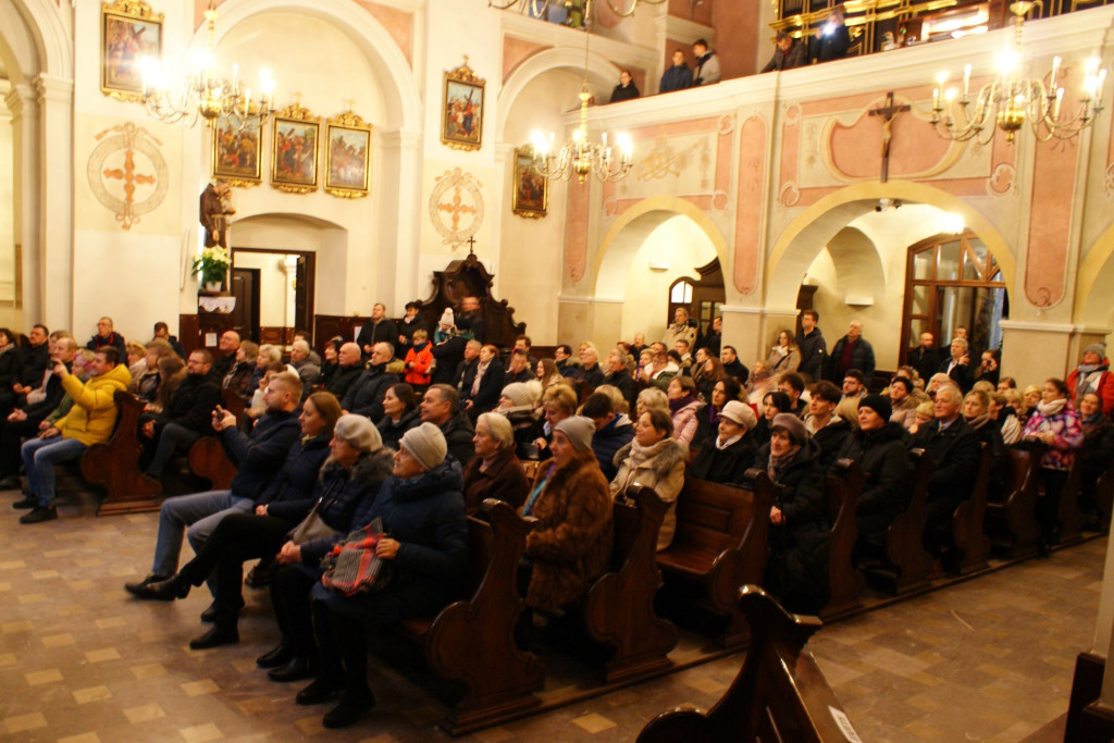 Chórzyści śpiewają na schodach prezbiterium Bazyliki Mniejszej w Tuchowie podczas koncertu kolęd