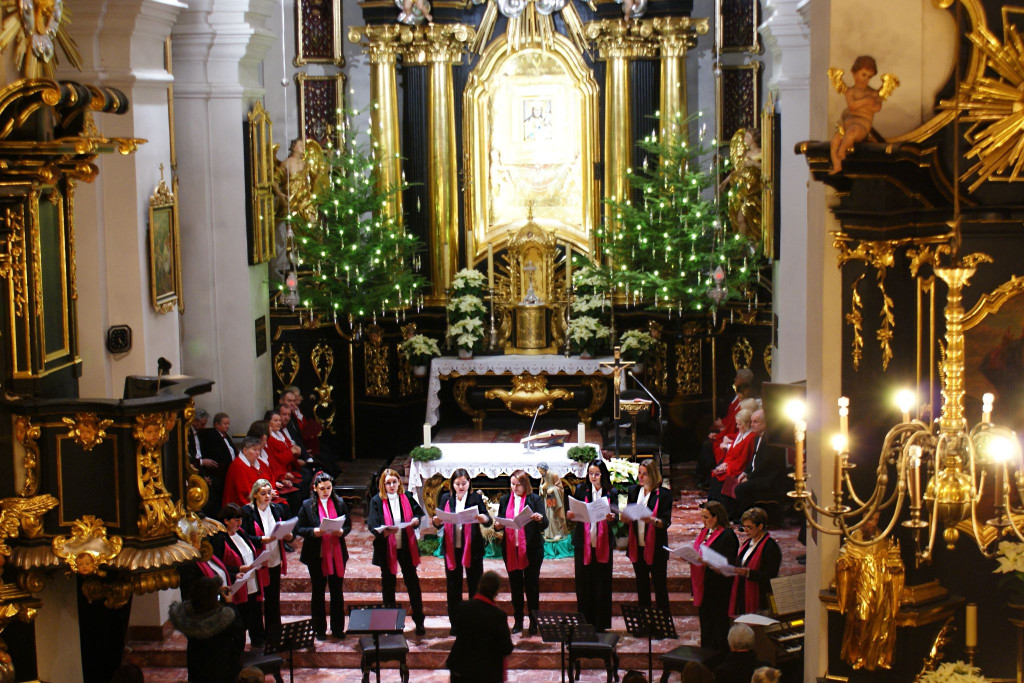 Chórzyści śpiewają na schodach prezbiterium Bazyliki Mniejszej w Tuchowie podczas koncertu kolęd